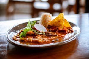 Close-up of a Mexican meal featuring rice, tortilla chips, and spicy sauce, perfect for cuisine lovers.
