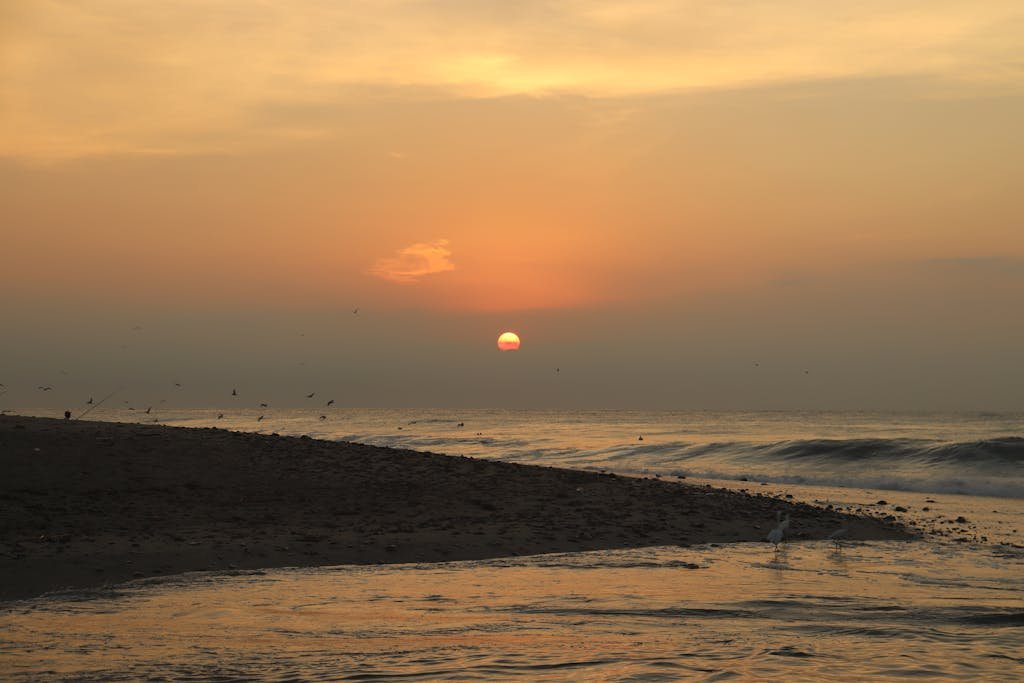Peaceful sunrise on a tranquil beach in Santa María Huatulco, Mexico, with gentle waves and birds.